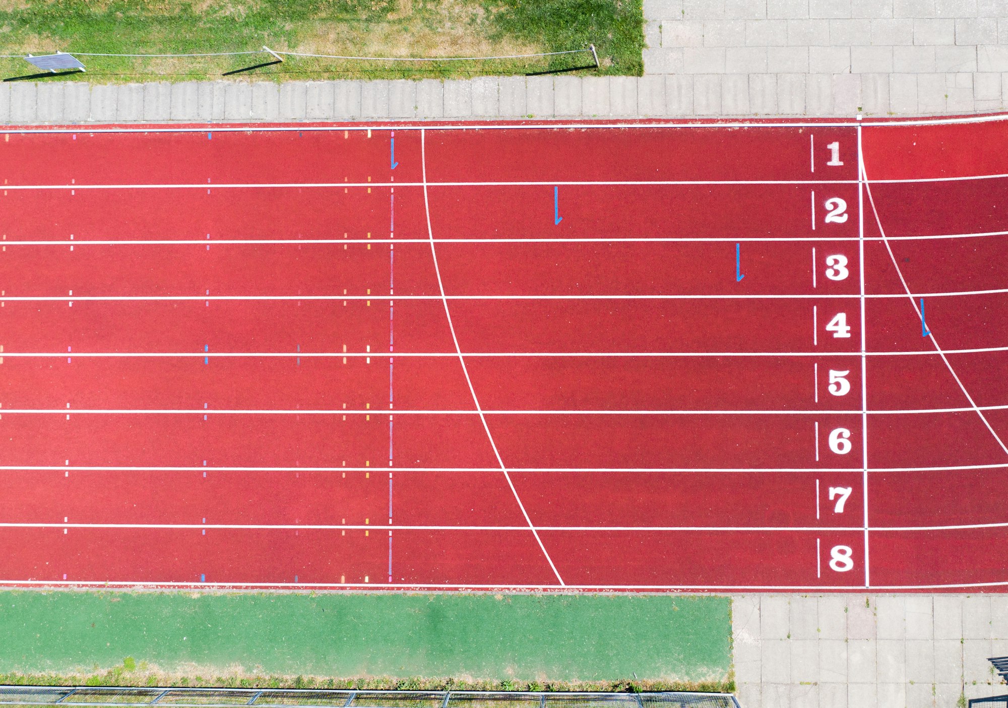 Aerial view of the finish line on an athletics track with numbered lanes and copy space