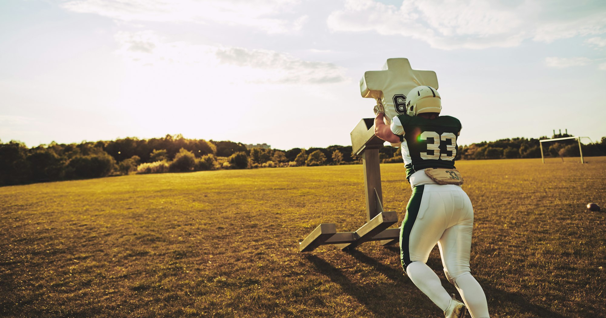 American football player doing tackling drills on a field