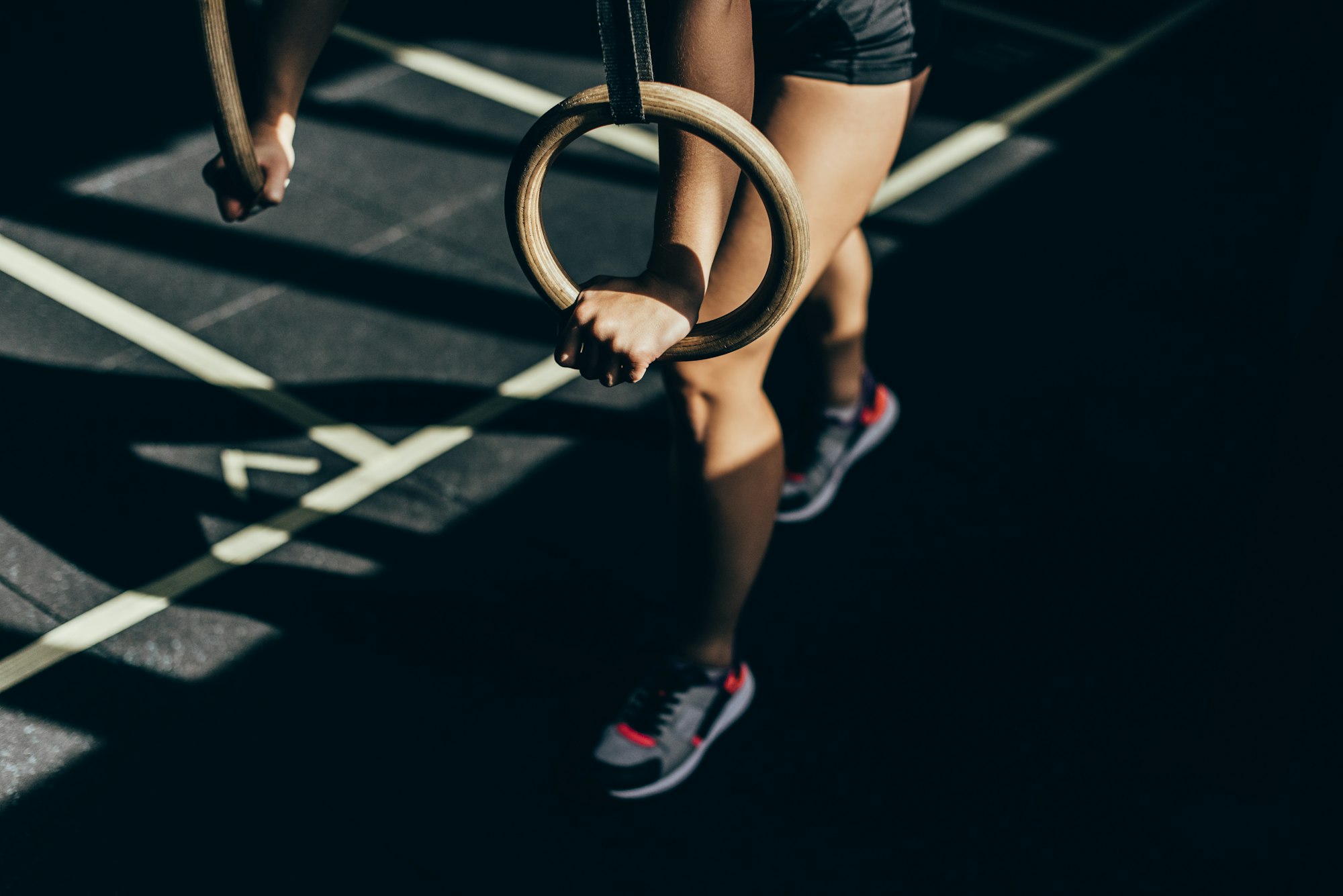 Cropped shot of athletic woman doing exercises with gymnastic rings at gym
