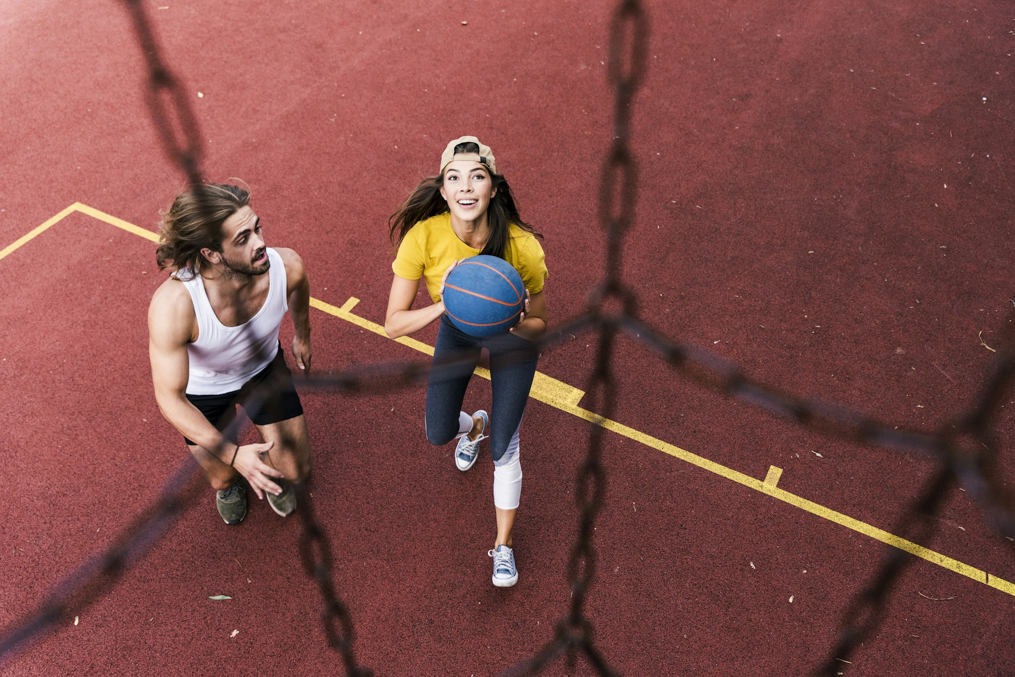 Young man and woman playing basketball on basketball ground